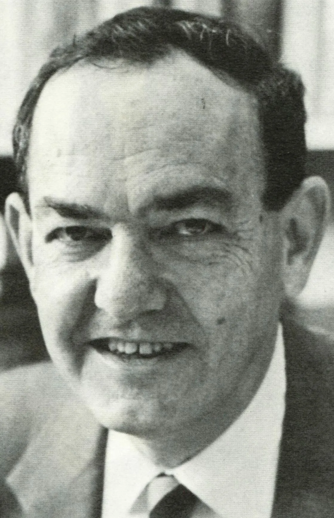Black-and-white photographic portrait of Herbert Simon smiling slightly, in a suit and tie.